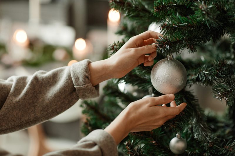 Hands Hanging Ornament on Christmas Tree